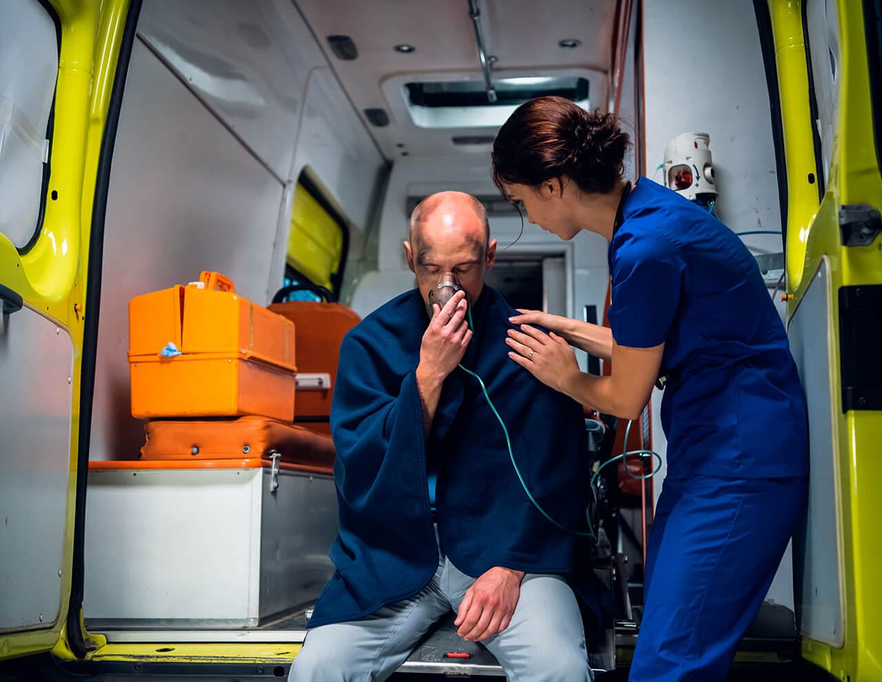 Mand i ambulance der får ilt af en paramediciner